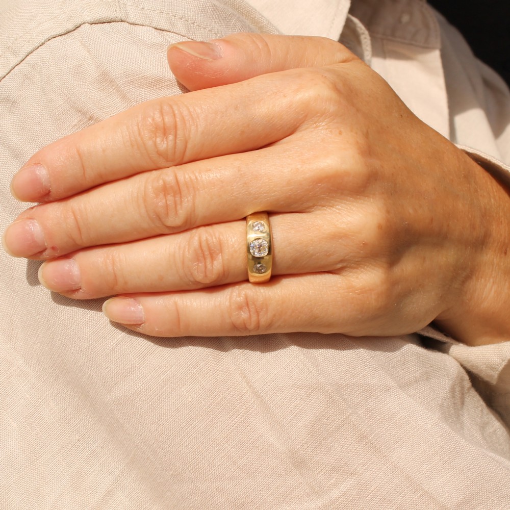 A smooth yellow gold wide band ring featuring three flush-set old cut diamonds across the front. View II