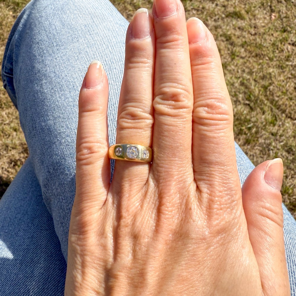A smooth yellow gold wide band ring featuring three flush-set old cut diamonds across the front. View VI