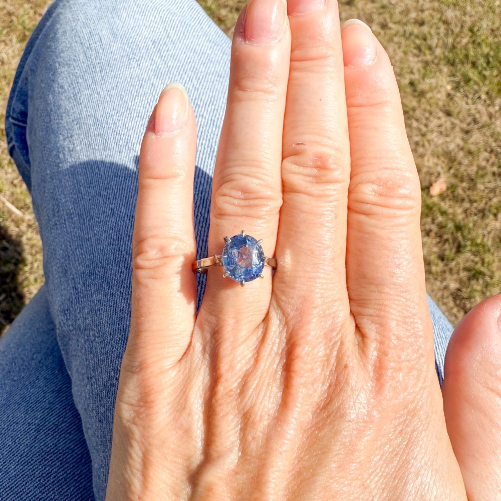 An Art Deco platinum solitaire ring featuring a large oval-cut light blue sapphire held in an eight-claw setting. View VI