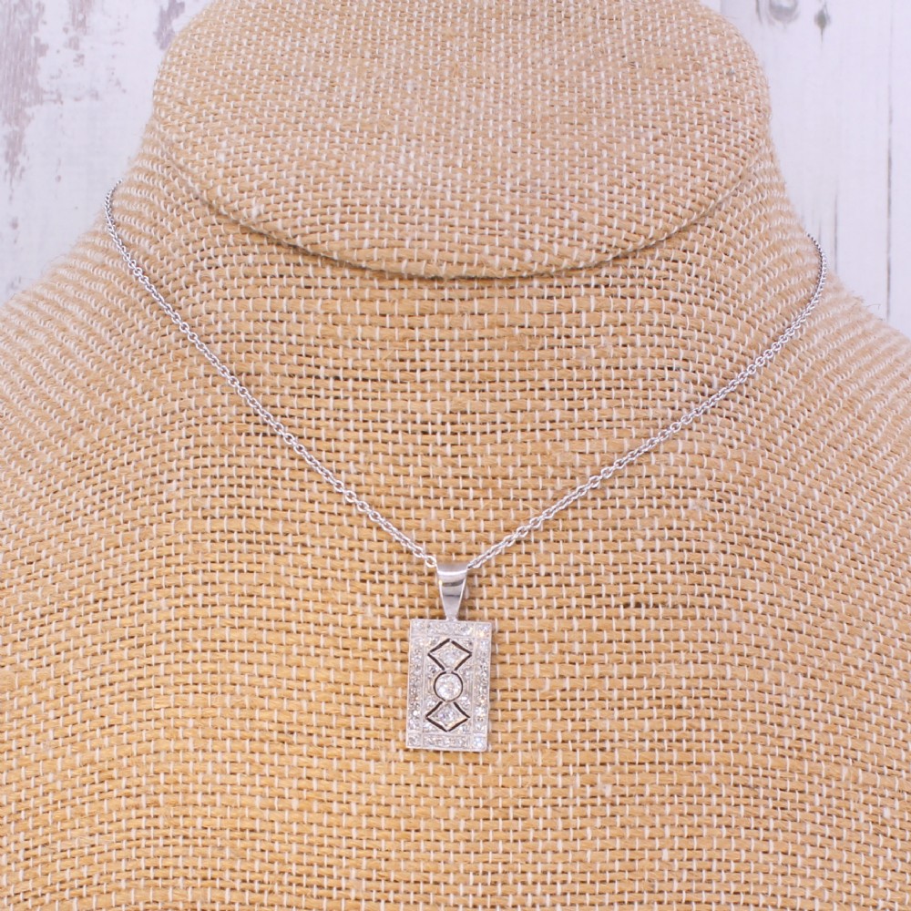 A rectangular Art Deco pendant set with a central round old cut diamond within a geometric diamond-paved frame on a silver chain. View VII