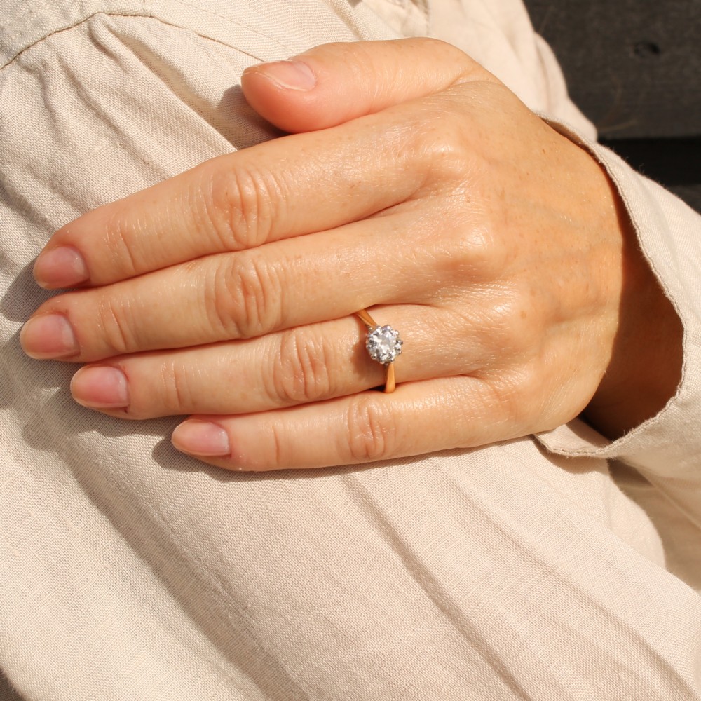 A vintage white metal engagement ring set with a central round old cut diamond flanked by small shoulder diamonds. View VII