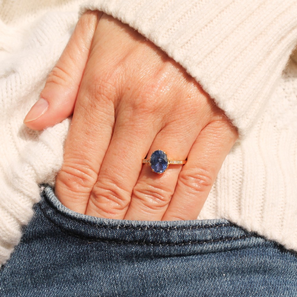 A vintage yellow gold ring featuring an oval-cut blue sapphire in a claw setting with diamond-set shoulders. View II