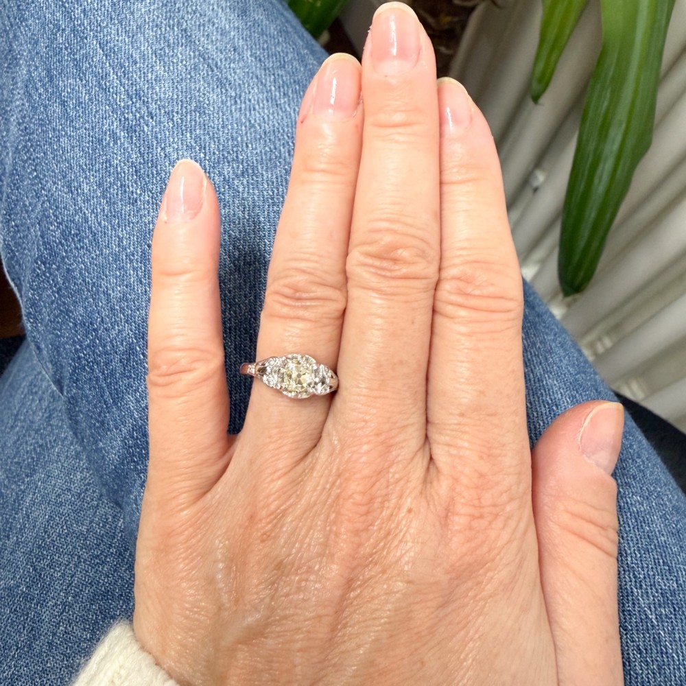 An Art Deco style white metal ring featuring a central old European cut diamond set in an ornate pierced basket setting. View VII