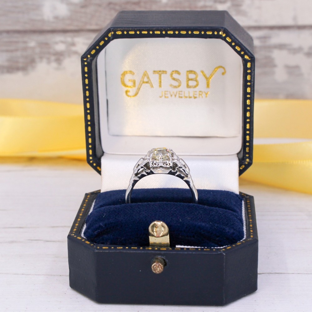 An Art Deco style white metal ring featuring a central old European cut diamond set in an ornate pierced basket setting. View IX