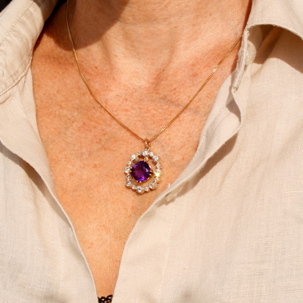 An antique yellow gold pendant featuring a central cushion-cut purple amethyst encircled by an openwork gold border and a halo of old-cut diamonds. View III