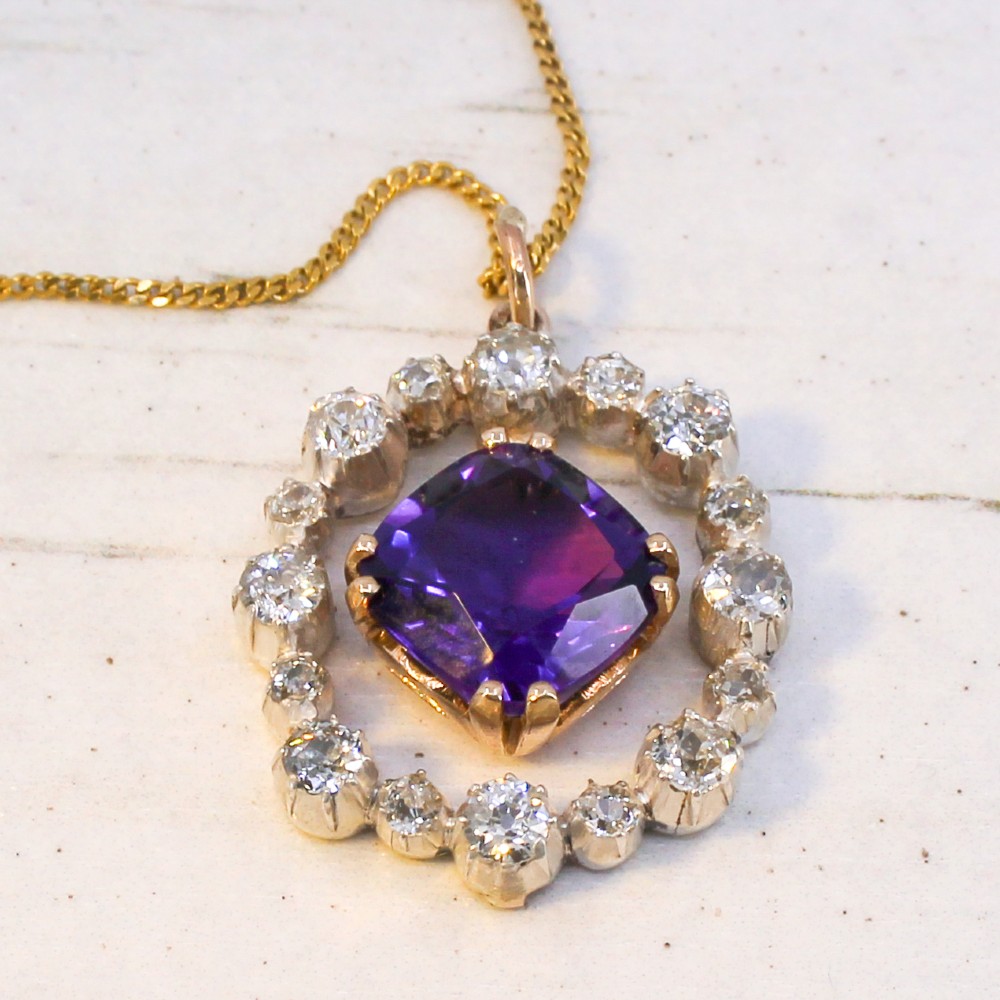 An antique yellow gold pendant featuring a central cushion-cut purple amethyst encircled by an openwork gold border and a halo of old-cut diamonds. View V