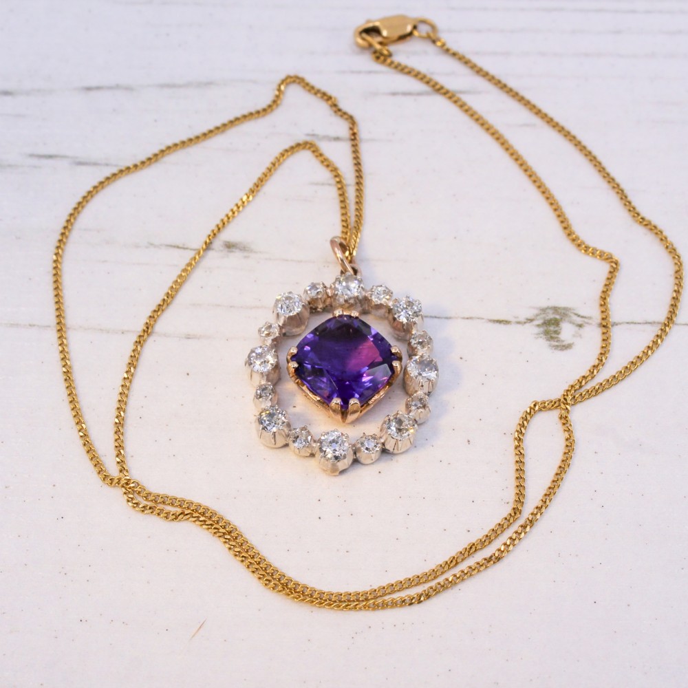 An antique yellow gold pendant featuring a central cushion-cut purple amethyst encircled by an openwork gold border and a halo of old-cut diamonds. View VI
