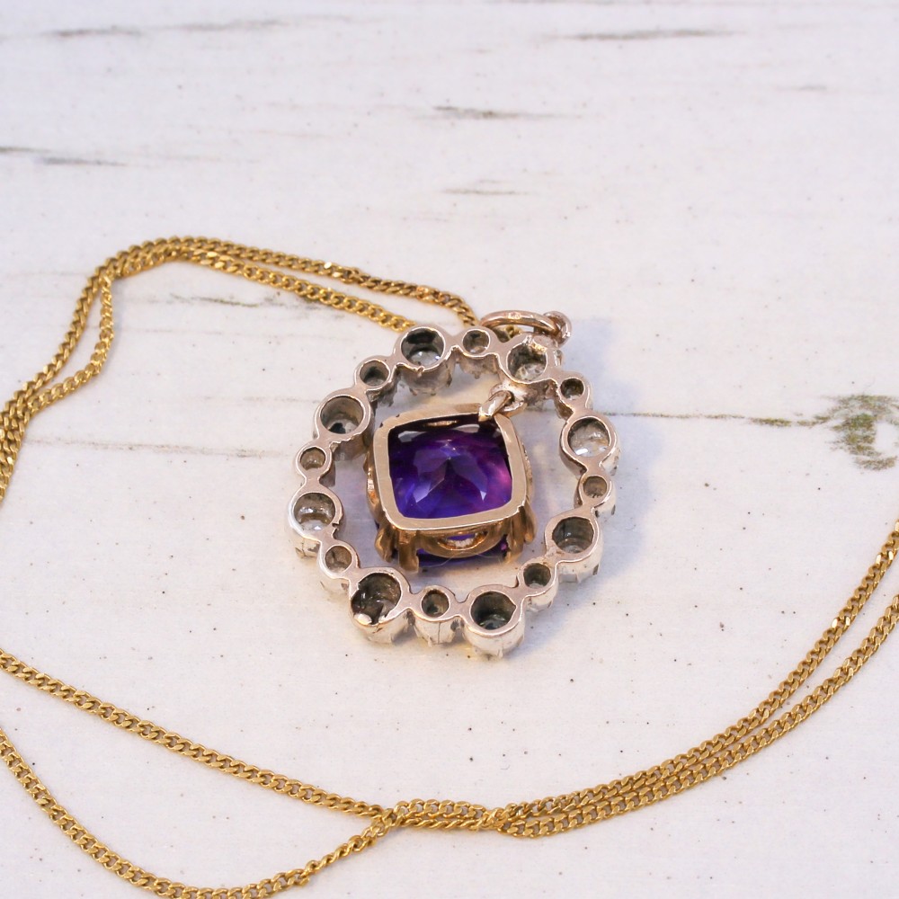 An antique yellow gold pendant featuring a central cushion-cut purple amethyst encircled by an openwork gold border and a halo of old-cut diamonds. View VIII