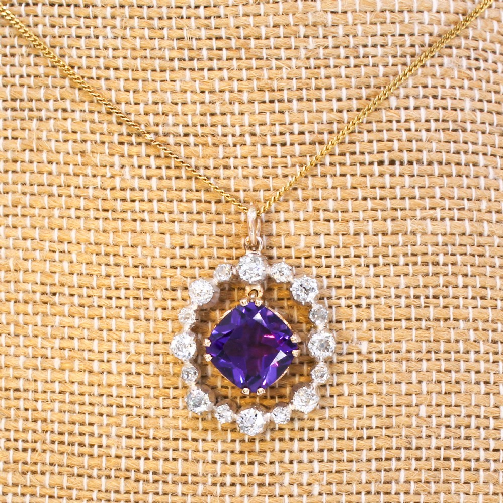 An antique yellow gold pendant featuring a central cushion-cut purple amethyst encircled by an openwork gold border and a halo of old-cut diamonds. View IX