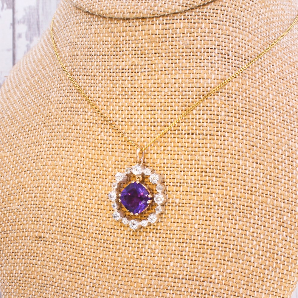 An antique yellow gold pendant featuring a central cushion-cut purple amethyst encircled by an openwork gold border and a halo of old-cut diamonds. View XI
