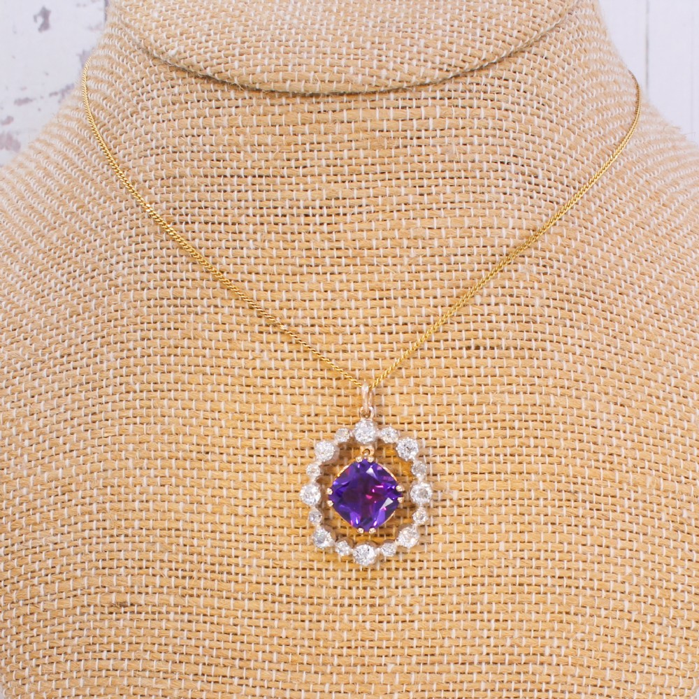 An antique yellow gold pendant featuring a central cushion-cut purple amethyst encircled by an openwork gold border and a halo of old-cut diamonds. View XIII