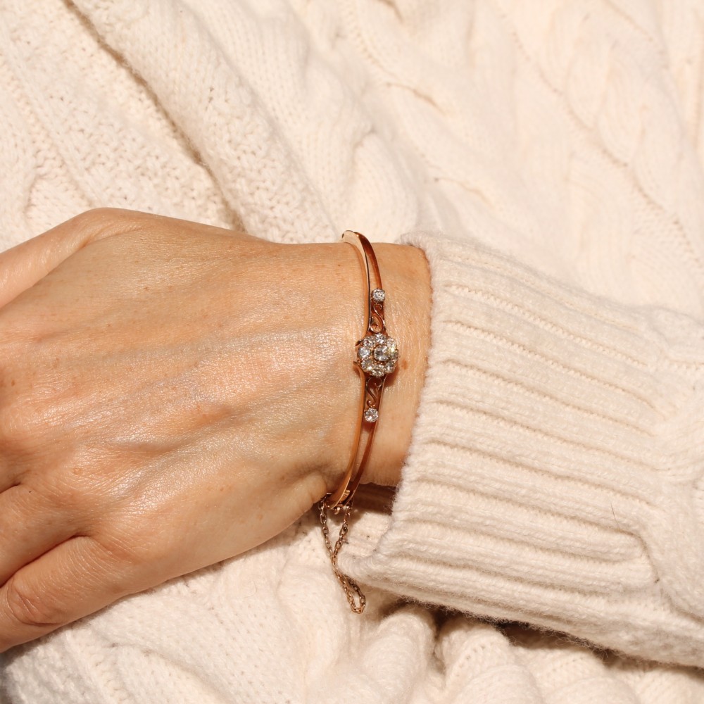A late Victorian yellow gold hinged bangle featuring a central old-cut diamond cluster flanked by scrollwork and accent diamonds. View III