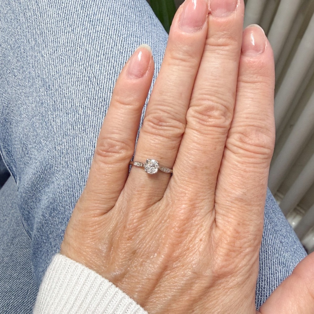A vintage platinum engagement ring featuring a round old cut central diamond flanked by small accent stones set into the shoulders. View VI