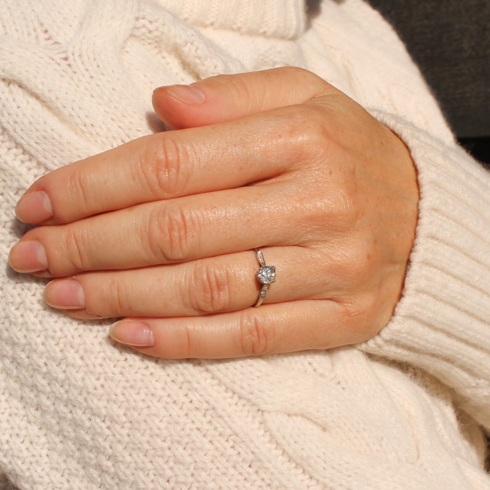 A vintage platinum engagement ring featuring a round old cut central diamond flanked by small accent stones set into the shoulders. View VII