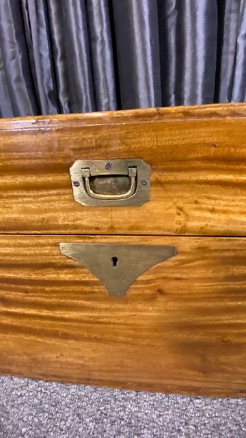 fig 1. A rectangular camphor wood military campaign chest featuring brass corner brackets, flush brass handles, and a central brass keyhole escutcheon.