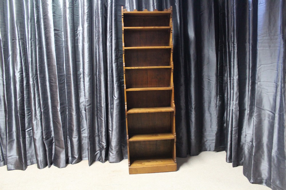 A tall antique elm open bookcase featuring seven shelves with decorative scalloped side profiles.