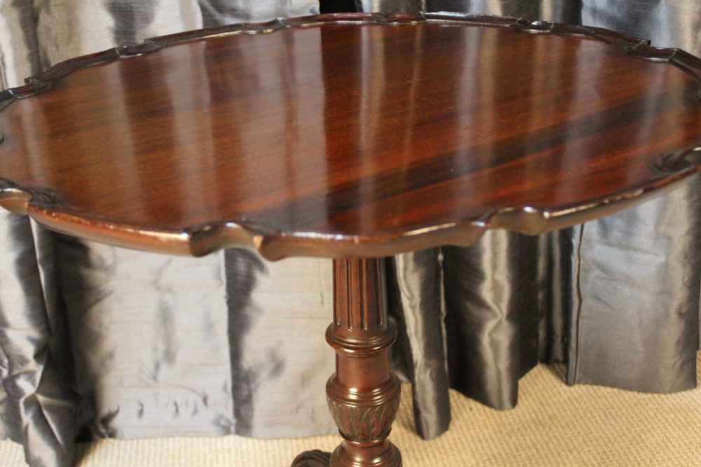 A mahogany tilt-top occasional table featuring a scalloped piecrust rim, turned column, and carved tripod legs. View III