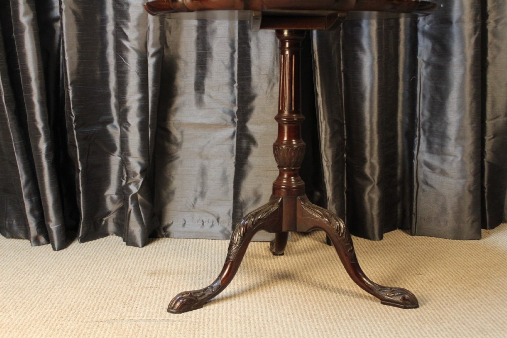 A mahogany tilt-top occasional table featuring a scalloped piecrust rim, turned column, and carved tripod legs. View VII