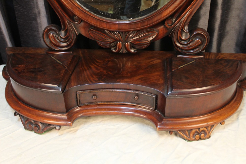 A Victorian mahogany dressing table mirror with an oval glass frame supported by carved scroll pillars on a plinth base. View II