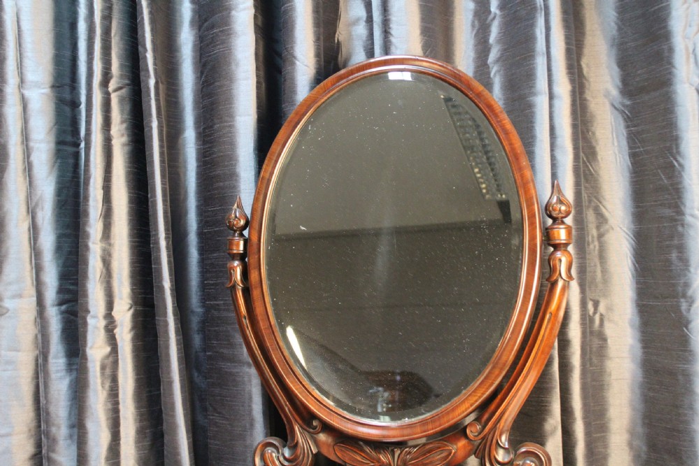 A Victorian mahogany dressing table mirror with an oval glass frame supported by carved scroll pillars on a plinth base. View III