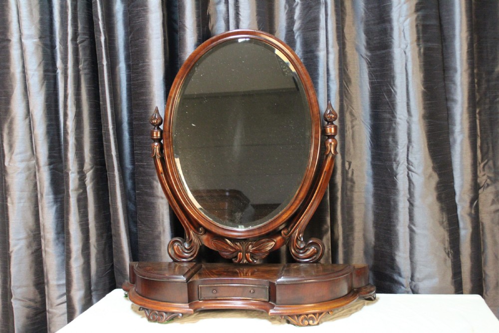 A Victorian mahogany dressing table mirror with an oval glass frame supported by carved scroll pillars on a plinth base. View IV