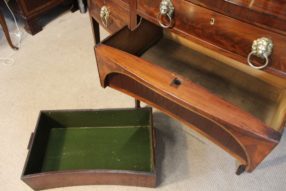 A mahogany bowfront sideboard featuring lion mask brass ring handles, boxwood stringing inlay, square tapered legs with spade feet, and an upper brass rail gallery. View V