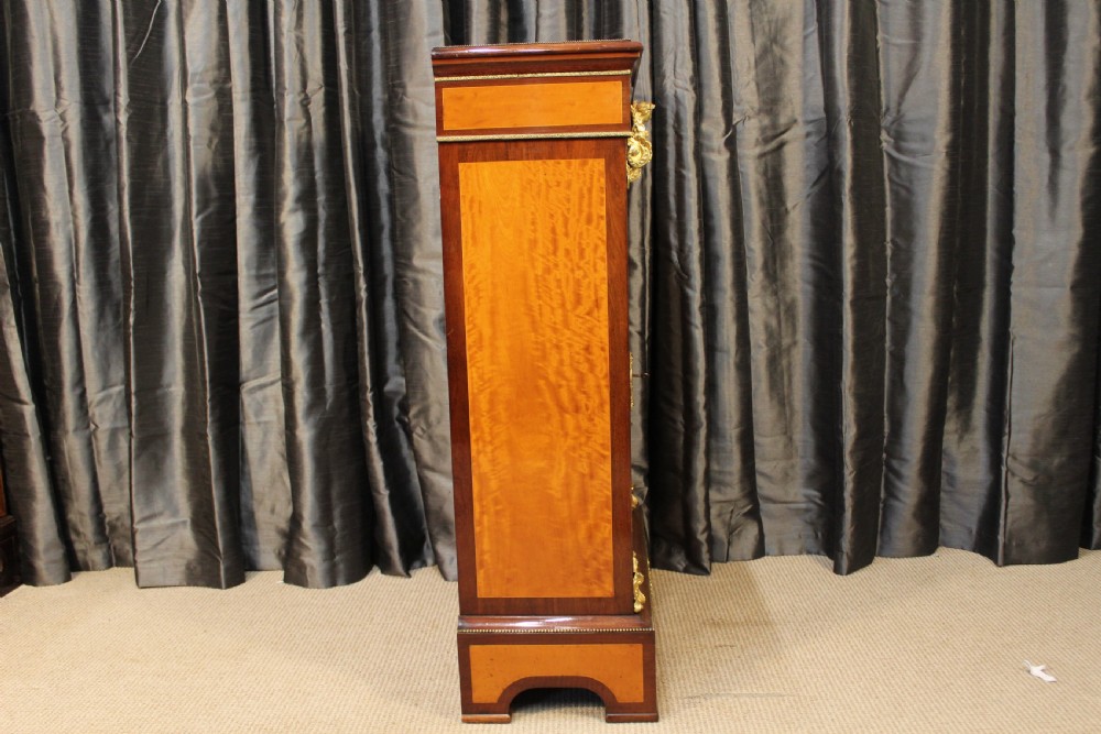 An antique warm brown timber cabinet featuring a glazed front door, ornamental gilt metal mounts, and porcelain floral plaques. View VIII