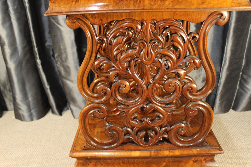 A Victorian burr walnut music Canterbury featuring a carved fretwork gallery, vertical scroll partitions, a lower drawer, and turned legs with castors. View II