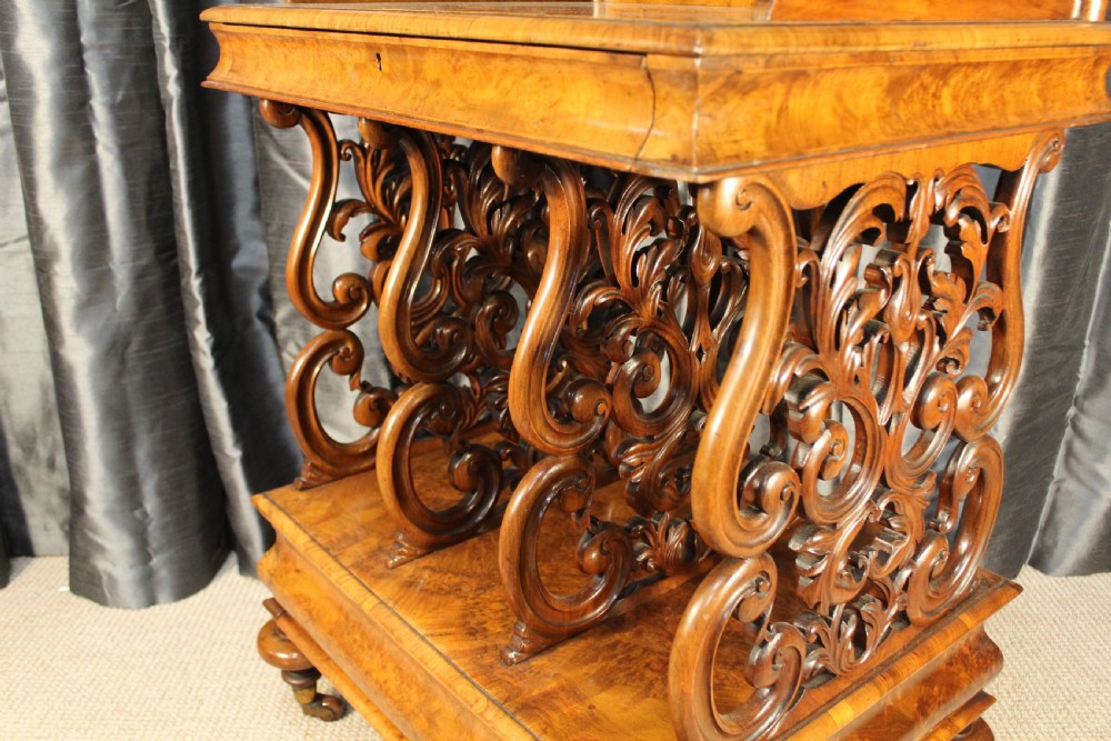 A Victorian burr walnut music Canterbury featuring a carved fretwork gallery, vertical scroll partitions, a lower drawer, and turned legs with castors. View III