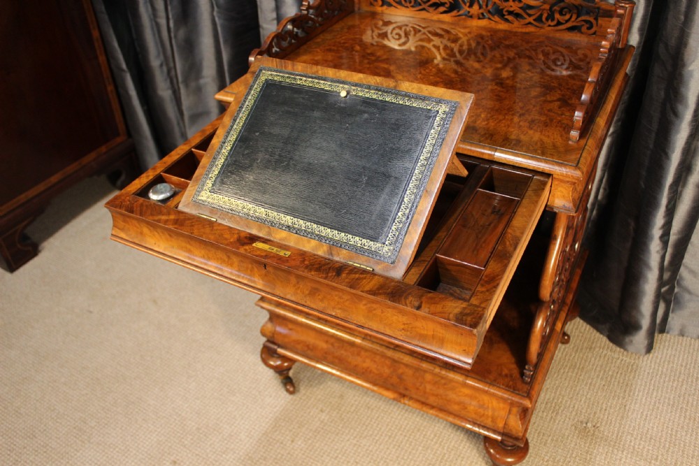 A Victorian burr walnut music Canterbury featuring a carved fretwork gallery, vertical scroll partitions, a lower drawer, and turned legs with castors. View VII