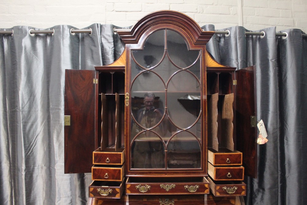 An antique mahogany bureau bookcase featuring an arched glazed upper door, oval marquetry inlays, a slant-front writing desk, four drawers with brass handles, and bracket feet. View III