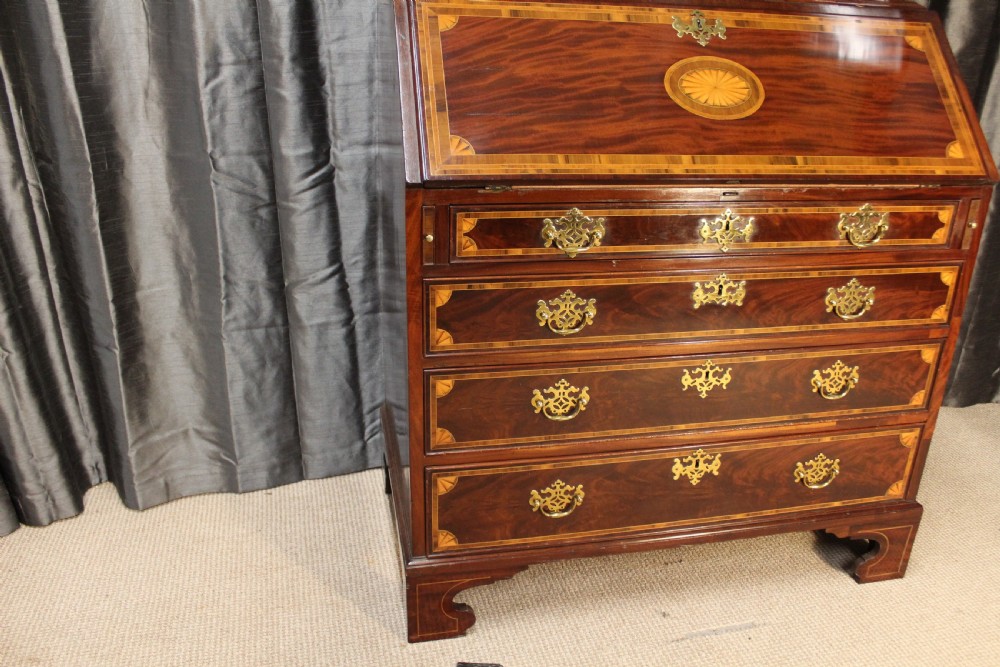 An antique mahogany bureau bookcase featuring an arched glazed upper door, oval marquetry inlays, a slant-front writing desk, four drawers with brass handles, and bracket feet. View VI