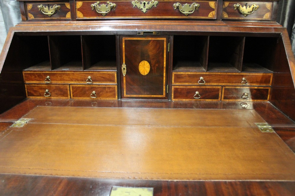 An antique mahogany bureau bookcase featuring an arched glazed upper door, oval marquetry inlays, a slant-front writing desk, four drawers with brass handles, and bracket feet. View VIII