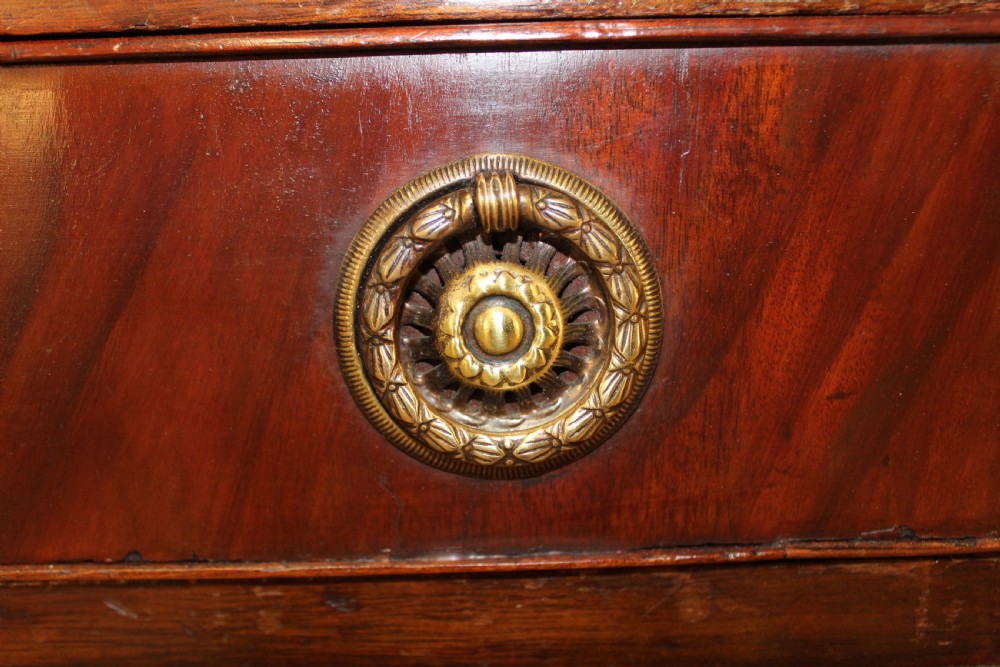 An antique mahogany pedestal desk with nine drawers, circular brass ring handles, flame mahogany drawer fronts, and bracket feet. View V