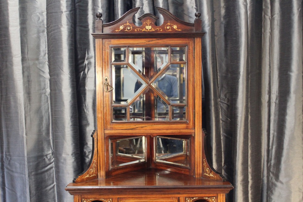 An antique dark wood corner display cabinet featuring delicate marquetry inlays, a glazed upper door, mirrored back sections, and open corner shelving. View II