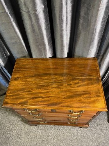 A mahogany chest of drawers featuring two short drawers above three long graduated drawers, fitted with brass swan-neck handles and raised on bracket feet. View IV
