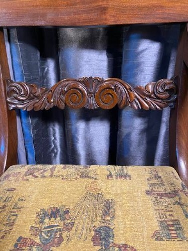 An antique mahogany carver chair featuring scrolled armrests, a foliate carved back rail, and patterned fabric upholstery. View III