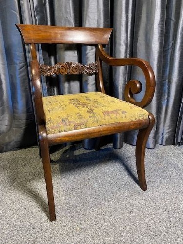 An antique mahogany carver chair featuring scrolled armrests, a foliate carved back rail, and patterned fabric upholstery. View IV