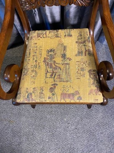 An antique mahogany carver chair featuring scrolled armrests, a foliate carved back rail, and patterned fabric upholstery. View V