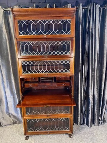 A tall dark mahogany sectional barrister bookcase with five leaded glass door compartments and a central wooden drop-front panel. View II