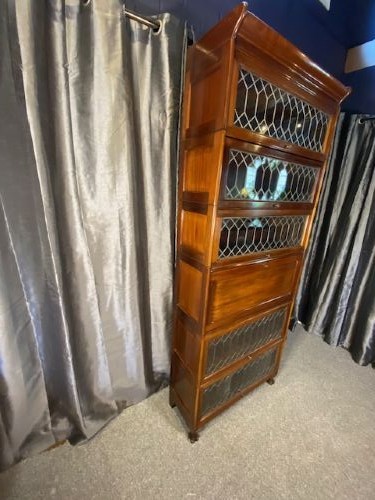 A tall dark mahogany sectional barrister bookcase with five leaded glass door compartments and a central wooden drop-front panel. View III