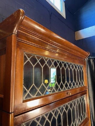 A tall dark mahogany sectional barrister bookcase with five leaded glass door compartments and a central wooden drop-front panel. View IV