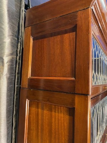 A tall dark mahogany sectional barrister bookcase with five leaded glass door compartments and a central wooden drop-front panel. View VI
