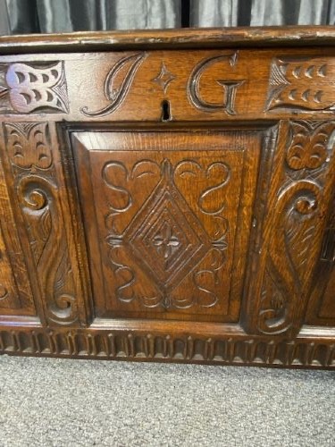 A dark carved oak coffer with three front panels featuring lozenge carvings and a carved upper rail. View II