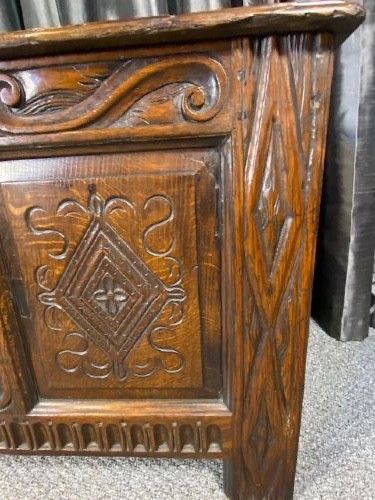 A dark carved oak coffer with three front panels featuring lozenge carvings and a carved upper rail. View V