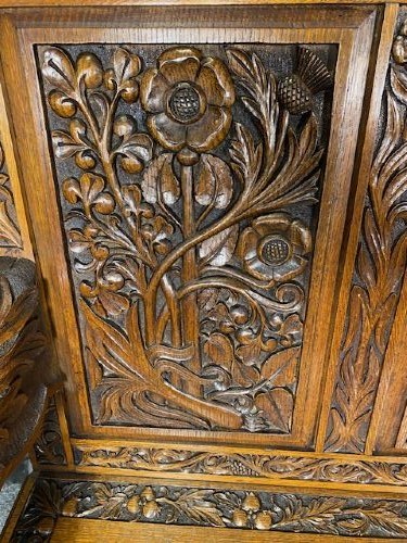 An Edwardian carved oak hall bench dated 1906, featuring mythological beast motifs, foliage panels, carved beast head armrests, and two lower drawers. View III