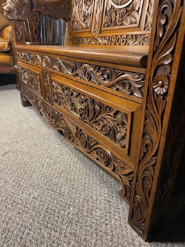 An Edwardian carved oak hall bench dated 1906, featuring mythological beast motifs, foliage panels, carved beast head armrests, and two lower drawers. View V