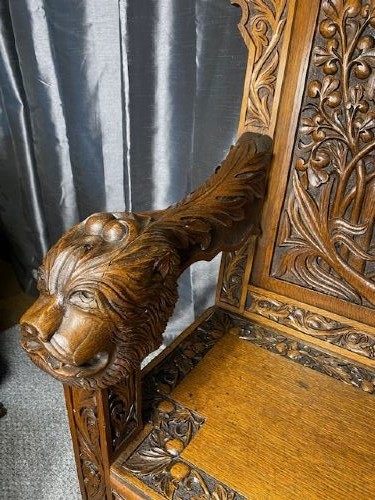 An Edwardian carved oak hall bench dated 1906, featuring mythological beast motifs, foliage panels, carved beast head armrests, and two lower drawers. View VII