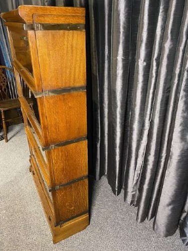 A four-tier warm brown oak barrister bookcase featuring glazed lift-and-slide doors and a single bottom drawer. View VI