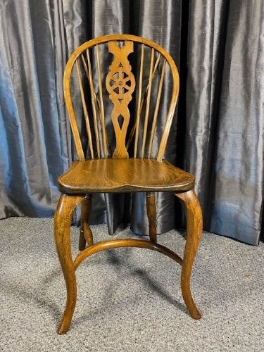 A set of six warm brown wooden Windsor dining chairs featuring hoop backs, pierced wheelback splats, shaped solid seats, and curved legs. View VI